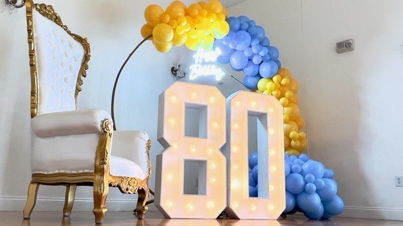 80th birthday with marquee 80, throne chair and blue and gold balloon ring